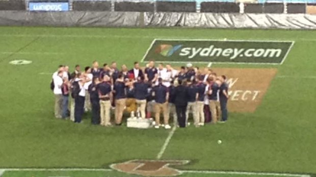 Huddle heroes ... Sydney Roosters players and staff at ANZ Stadium after the grand final win in 2013.