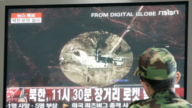 A South Korean Army soldier watches a TV news reporting a rocket launched by North Korea at a train station in Seoul.