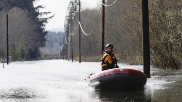 A search and rescue worker rides a boat along a flooded portion of Highway 530.