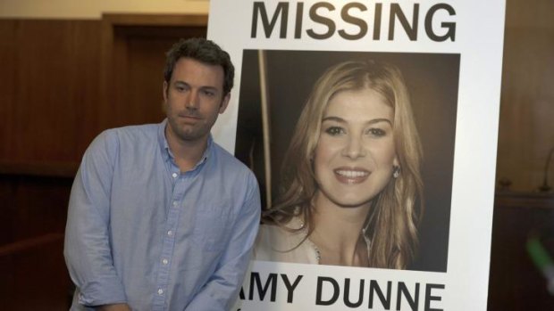 Ben Affleck in <i>Gone Girl</i> with a poster of his missing wife played by Rosamund Pike.