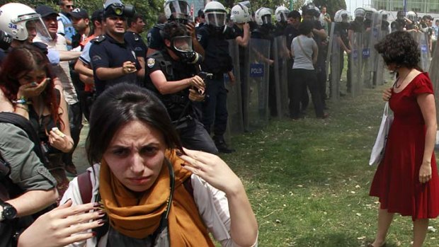 Reluctant heroine: a riot policeman prepares to use tear gas against Ceyda Sungur.