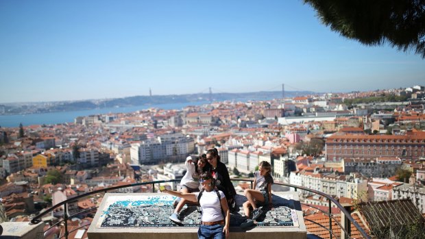 Tourists pose for a selfie at the Nossa Senhora do Monte or 'Our Lady of the Hill' viewpoint overlooking Lisbon, Portugal. The hilly Portuguese capital has several viewpoints where locals and tourists enjoy the view from difference parts of the city. 