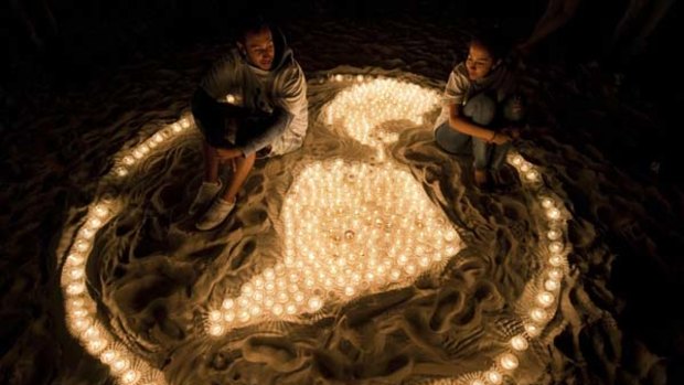 Members of the World Wildlife Fund sit among lit candles forming a representation of the Earth during a demonstration in a beach of Cancun.