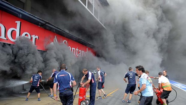 Racing team crews try to extinguish a fire in the Williams racing pit after the Spanish Grand Prix.