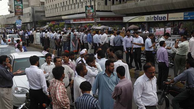 People stand outside of their office buildings following an earthquake tremor in Karachi.