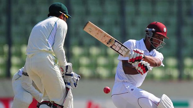 Kieran Powell sweeps as Bangladesh captain, wicketkeeper Mushfiqur Rahim, tries to block the shot.