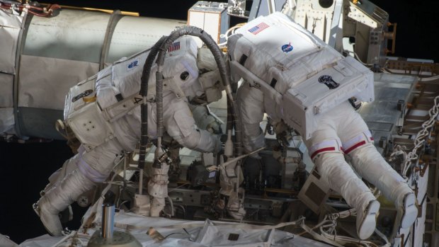 Scott Kelly (at left) undertaking a dangerous space walk outside the International Space Station.