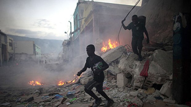 Looters run with goods from a destroyed store in downtown Port-au-Prince.