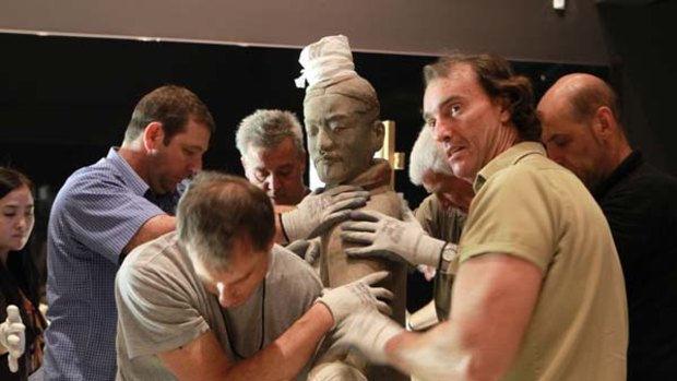 Who's protecting whom? ... gallery workers  take great care unpacking and positioning a  terracotta figure in preparation for the exhibition.