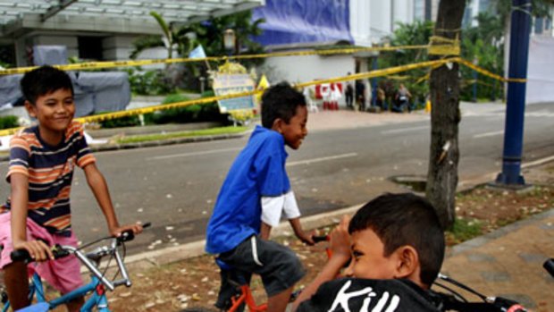 Children on their bikes outside the Ritz-Carlton Hotel in Jakarta yesterday, nine days after it was damaged in a suicide bomb attack.