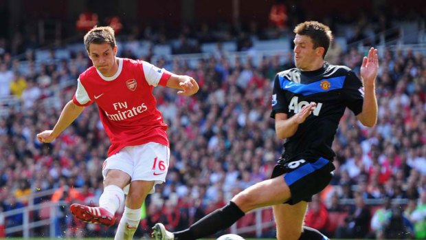 Aaron Ramsey of Arsenal shoots past Manchester United's Michael Carrick to score a goal.