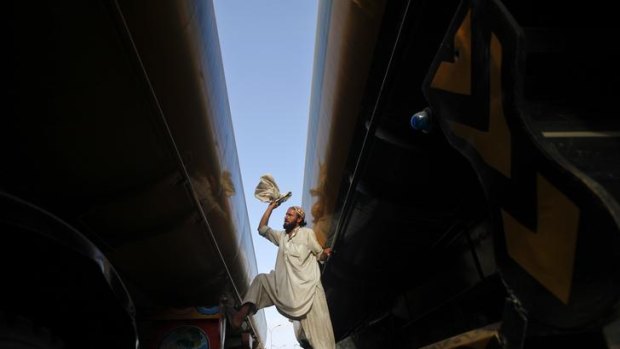 A man cleans a fuel tanker, which was used to carry fuel for NATO forces in Afghanistan, parked at a compound in Karachi, Pakistan.