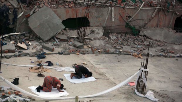Evening prayers: Two men pray at the site of the collapsed garment factory building.
