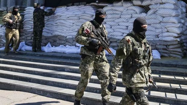Who are these masked men? Pro-Russian armed men walk past the mayor's office in Slaviansk, Ukraine.