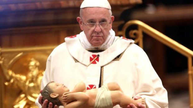 Pope Francis holds the crib effigy of the infant Jesus as he attends the Christmas Eve night mass at the St. Peter's Basilica.