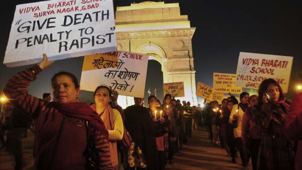 Indian people hold placards as they participate in a candlelight vigil at India Gate in New Delhi