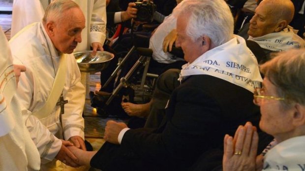 Pope Francis washing the feet of a disabled man.