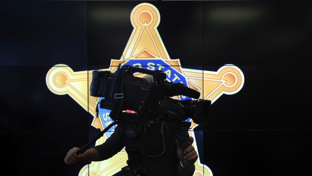 A television cameraman records a news conference in front of the US Secret Service logo, attended by Homeland Security Secretary Jeh Johnson, about the security for the presidential inauguration and activities related to it.