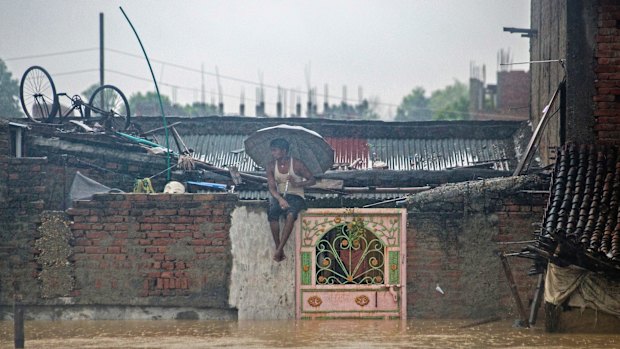 A Nepalese man sits on the wall of his house in a partially submerged village in Birgunj, Nepal, on Sunday.