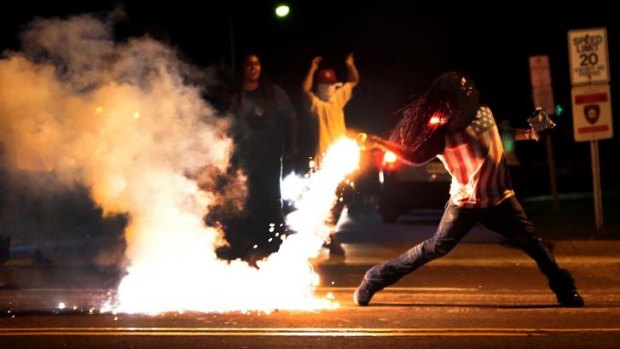 A demonstrator throws a tear gas container back towards tactical police in Ferguson, St Louis, on Wednesday night.