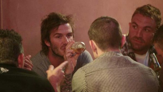 Cheers ...   David Beckham enjoys a beer at the Newcastle cafe Goldbergs last night. The injured Newcastle Jets player Ljubo Milicevic is on the right.