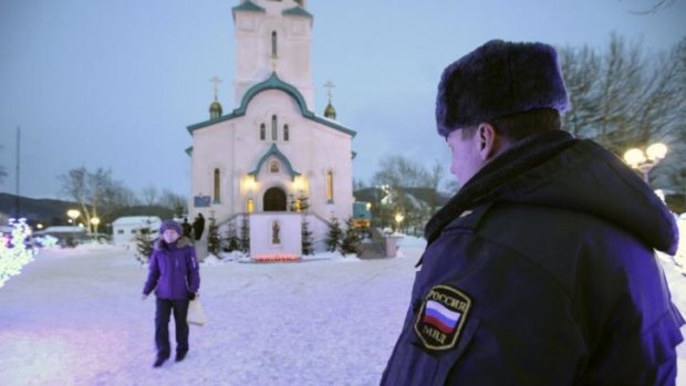 Fatal attack: A policeman watches a parishioner leaving the Cathedral of the Resurrection of Christ in Yuzhno-Sakhalinsk.