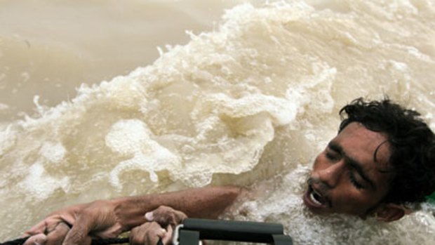 Head above water ... Mohammed Nawaz, after swimming for hours, clings to the navy craft that plucked him from floodwaters sweeping south into Sukkur, in Sindh province.