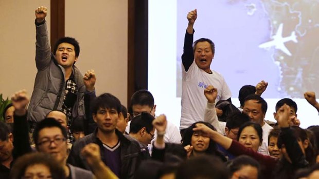 "Return our families": Family members of passengers onboard MH370 raise their fists in protest at a government briefing over the missing plane.