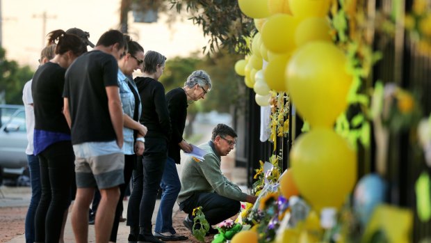 Merrilyn Scott (2nd from right) and Robert Scott (right) parents of murdered woman Stephanie Scott who went missing on Easter Sunday, look at the messages at the floral memorial on the gates of the Leeton High School where his Stephanie Scott worked. 