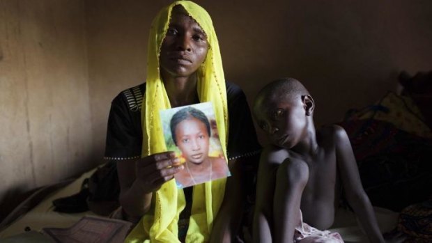 Rachel Daniel, 35, holds up a picture of her abducted daughter Rose Daniel, 17, as her son Bukar, 7, sits beside her at her home in Maiduguri in May. Another 25 girls have been abducted by suspected Boko Haram fighters.