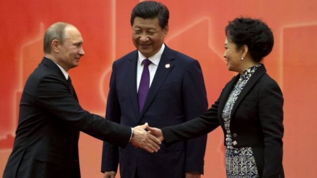 Bridging the divide: Russian President Vladimir Putin greets Chinese first lady Peng Liyuan as Chinese President Xi Jinping looks on in Shanghai.