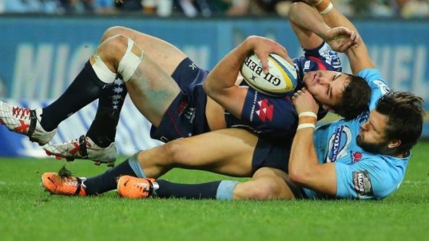 Tom English of the Rebels is tackled by Adam Ashley-Cooper of the Waratahs.