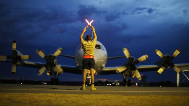 A ground controller guides a Royal Australian Air Force P-3 Orion to rest in Perth after another day of scouring the Indian Ocean.