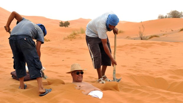 Sun and sand of a different kind: A tourist takes a sand bath in the dunes of the Merzouga desert in southeastern Morocco.