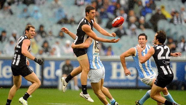 Unbelievable touch: Scott Pendlebury feeds out a handball, in mid-air, while being tackled, against North Melbourne last month.