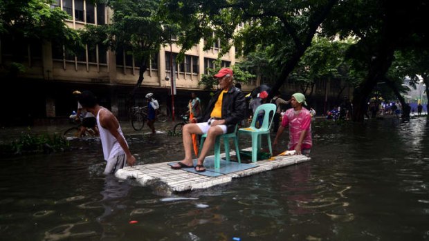 High and dry:  Makeshift rafts ferry  pedestrians through floodwaters that submerged parts of the financial district of Makati on Tuesday.