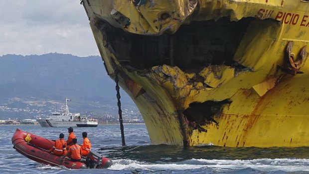 Deadly collision: Coastguard rescuers ride a rubber boat past the damaged bow of the Sulpicio Express 7 cargo vessel.