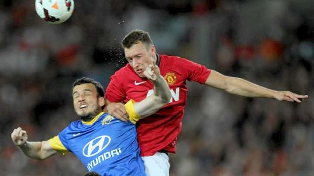 Surreal: Mark Bridge tussles with Manchester United star Phil Jones in the A-League Allstars match in July.