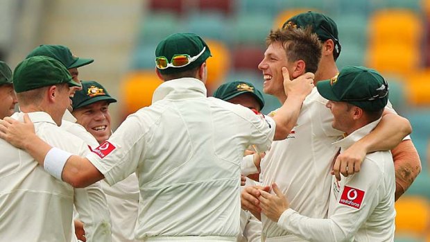 Teammates rush in to congratulate James Pattinson after he captured his first Test wicket at the Gabba yesterday.