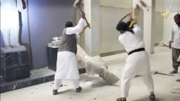 Men use sledgehammers on a toppled statue in a museum at a location said to be Mosul in this still image taken from an undated video. 