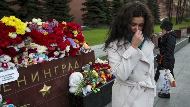 A woman cries after laying flowers at the memorial Tomb of the Unknown Soldier outside Moscow's Kremlin Wall in Moscow. Mourners have been laying wreaths, pictures of the victims, stuffed animals and paper planes since Metrojet's Airbus A321-200 crashed on Saturday, killing all 224 on board. 