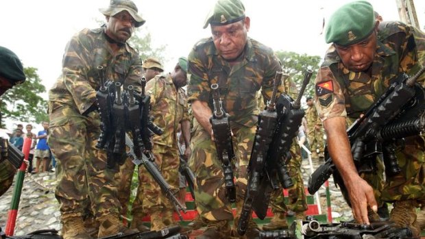 At ease: PNG soldiers at Tuarama Barracks hand back weapons to symbolise the end of the attempted uprising.