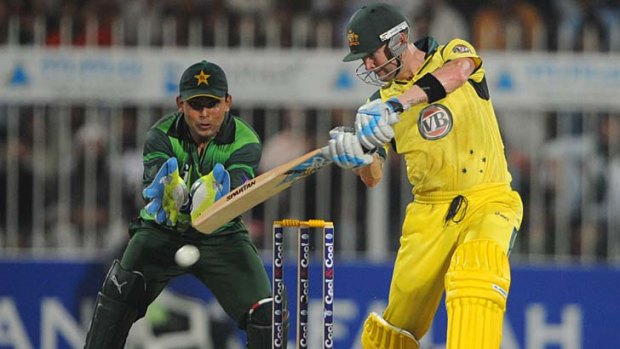 Australian captain Michael Clarke plays a shot as Pakistani wicketkeeper Kamran Akmal looks on.