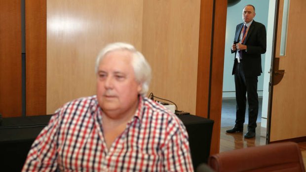 Clive Palmer adviser Ben Oquist stands behind the PUP leader before a press conference.