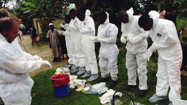 Volunteers prepare to remove the bodies of people who were suspected of contracting Ebola and died in the community in the village of Pendebu, Sierra Leone.
