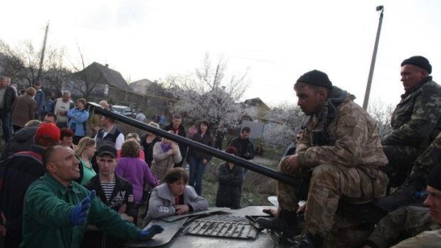 Ukrainian men sit on personnel carriers.