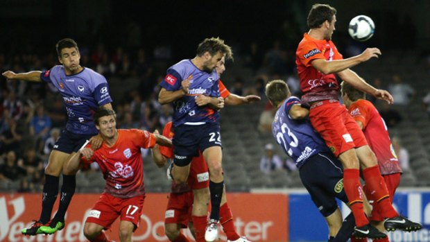 Melbourne and Adelaide players fly for a cross during the Victory's 2-0 win at Etihad Stadium on Saturday night.