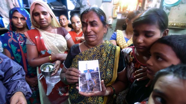 An Indian family member holds a picture of a victim of toxic home-made liquor consumption in Mumbai. 