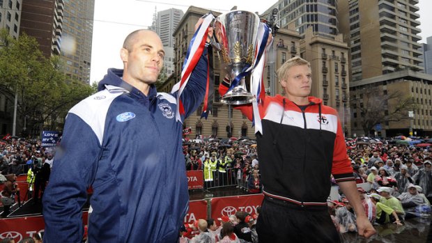 Same conditions but different teams. Geelong's Tom Harley and St Kilda's Nick Riewoldt hold the premiership cup at the rainy 2009 Grand Final parade.