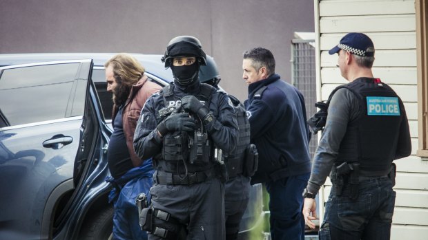 A man is led from a house by police during a terror raid in Ballarat Road, Braybrook, on Saturday, August 6.